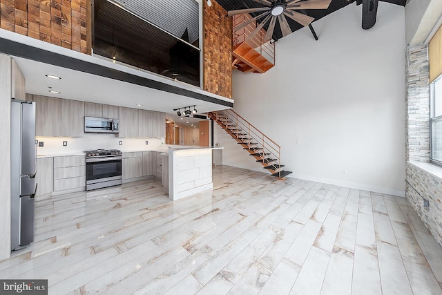 kitchen with light countertops, appliances with stainless steel finishes, modern cabinets, light wood-type flooring, and a peninsula