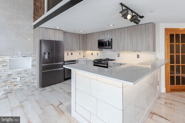 kitchen with light stone counters, recessed lighting, a peninsula, appliances with stainless steel finishes, and modern cabinets