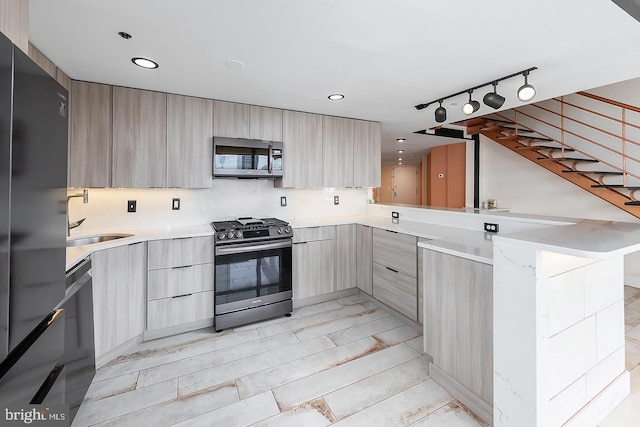 kitchen featuring stainless steel appliances, light brown cabinetry, modern cabinets, and a peninsula