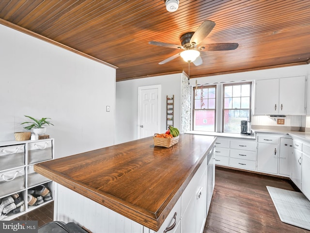 kitchen featuring wooden counters, a kitchen island, dark wood-type flooring, crown molding, and white cabinets