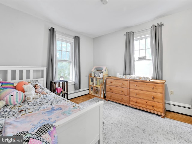 bedroom with a baseboard heating unit and wood finished floors