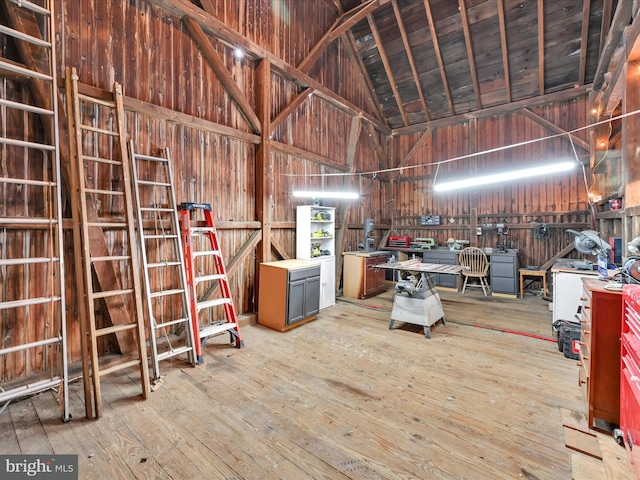 misc room featuring a workshop area, wood-type flooring, and high vaulted ceiling