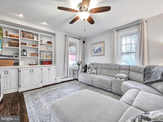 living area with a baseboard radiator, a healthy amount of sunlight, dark wood finished floors, and a ceiling fan