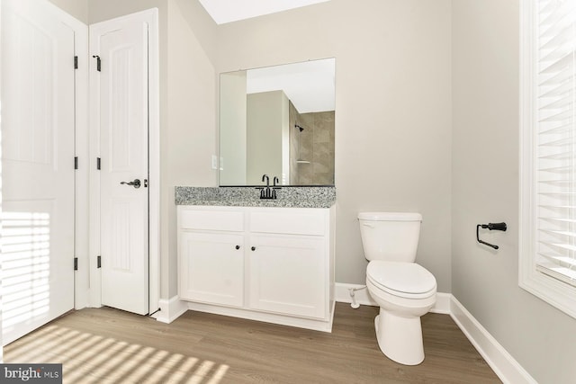 full bathroom featuring toilet, wood finished floors, vanity, a healthy amount of sunlight, and baseboards