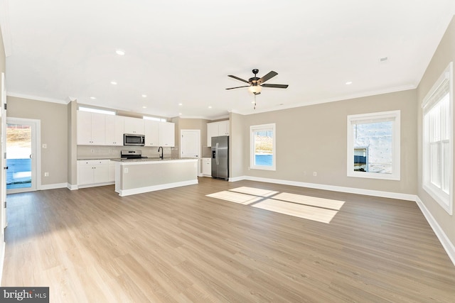 unfurnished living room featuring light wood finished floors, ornamental molding, and baseboards