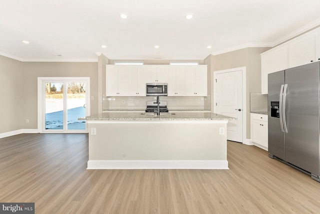 kitchen featuring an island with sink, white cabinetry, appliances with stainless steel finishes, and crown molding