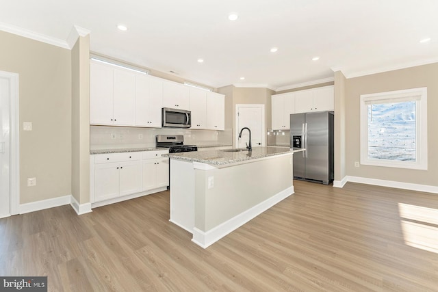 kitchen with stainless steel appliances, tasteful backsplash, a sink, and white cabinetry