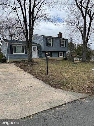 tri-level home featuring concrete driveway and a chimney