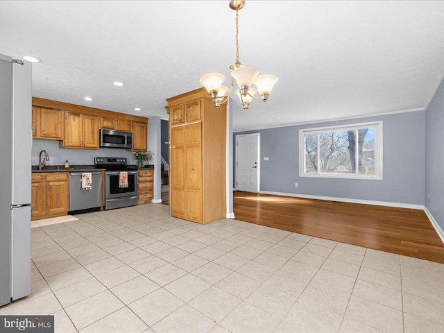 kitchen with dark countertops, open floor plan, light tile patterned floors, appliances with stainless steel finishes, and an inviting chandelier