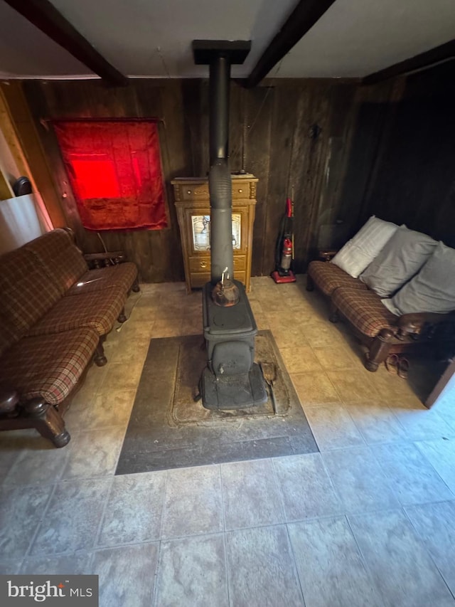 interior details with a wood stove, wooden walls, and beam ceiling