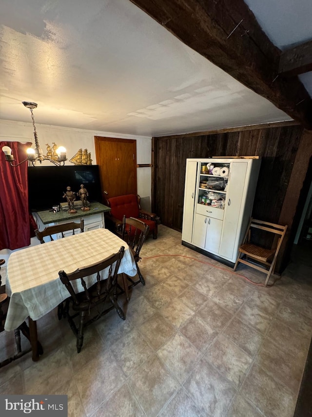 dining room with beamed ceiling, wooden walls, and an inviting chandelier