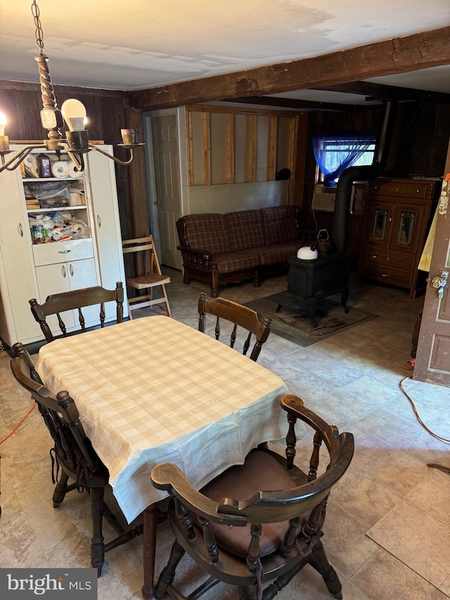 dining area featuring a chandelier, a wood stove, and wood walls