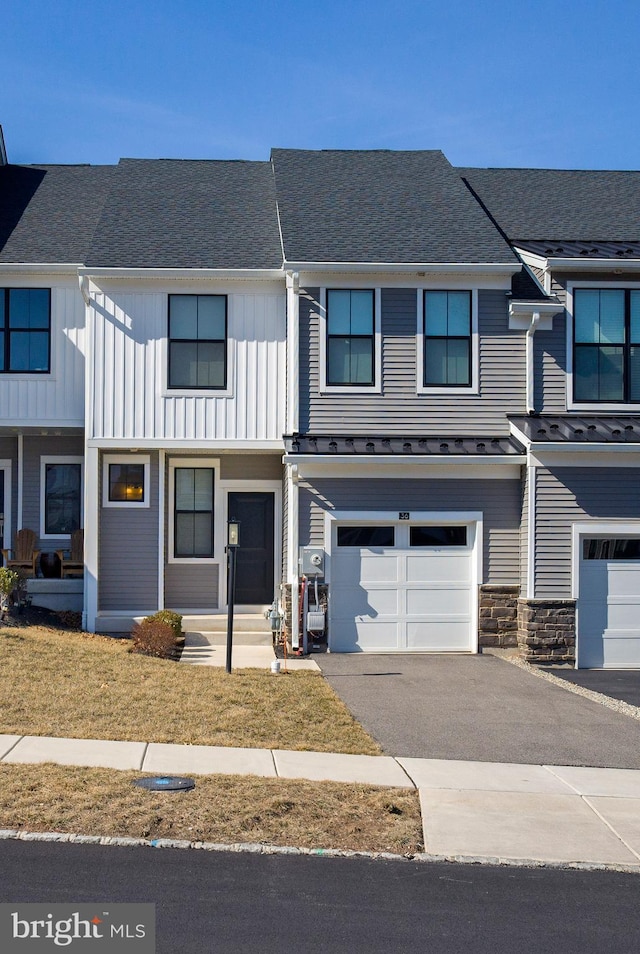 multi unit property featuring a shingled roof, a garage, stone siding, aphalt driveway, and board and batten siding