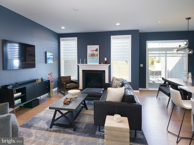 living room with a glass covered fireplace, recessed lighting, baseboards, and wood finished floors