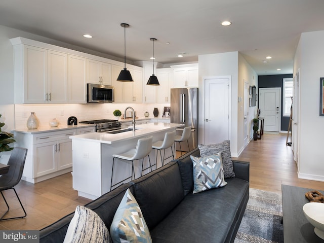 kitchen featuring light wood-type flooring, light countertops, high end appliances, and a sink