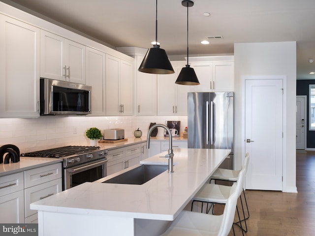 kitchen featuring a sink, tasteful backsplash, dark wood finished floors, stainless steel appliances, and white cabinets