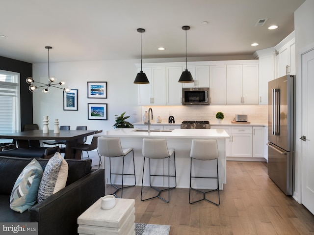 kitchen featuring visible vents, light wood finished floors, a sink, stainless steel appliances, and white cabinets