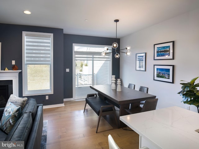 dining room featuring recessed lighting, an inviting chandelier, a fireplace, light wood finished floors, and baseboards