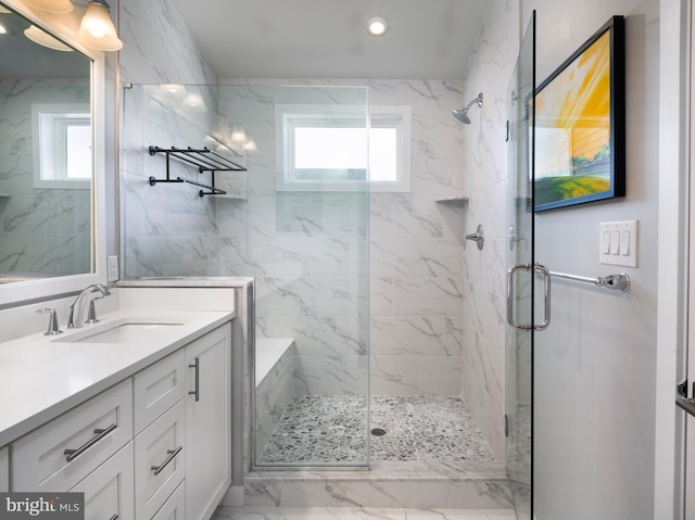 full bath featuring plenty of natural light, marble finish floor, a stall shower, and vanity