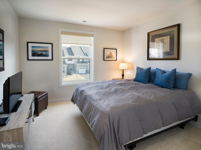 bedroom featuring visible vents, light carpet, and baseboards