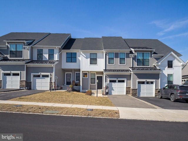 townhome / multi-family property featuring board and batten siding, an attached garage, stone siding, and driveway