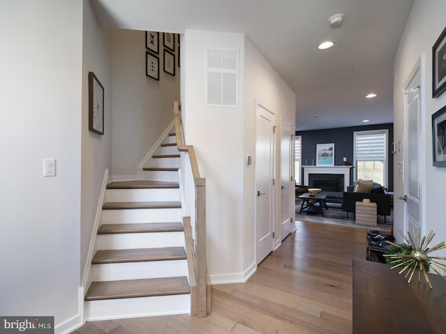 staircase with visible vents, baseboards, recessed lighting, a fireplace, and wood finished floors