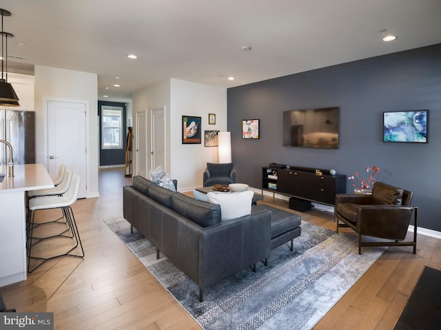 living room with recessed lighting, baseboards, and light wood-style floors