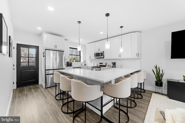 kitchen featuring appliances with stainless steel finishes, light countertops, a peninsula, and a breakfast bar area