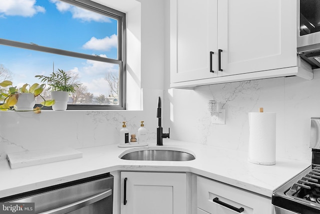 kitchen with white cabinetry, appliances with stainless steel finishes, backsplash, and a sink