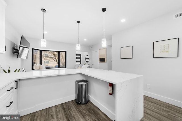 kitchen featuring dark wood-style flooring, visible vents, baseboards, white cabinets, and decorative light fixtures