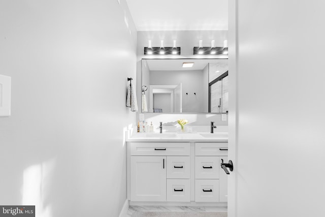 full bath with marble finish floor, a shower with shower door, a sink, and double vanity