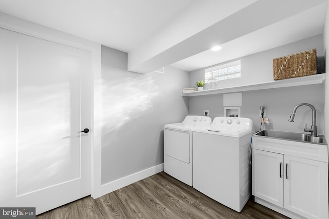 washroom with dark wood-type flooring, a sink, baseboards, washer and dryer, and cabinet space