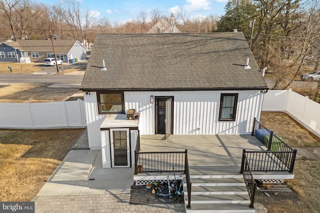 rear view of house with a shingled roof, a fenced backyard, and a yard