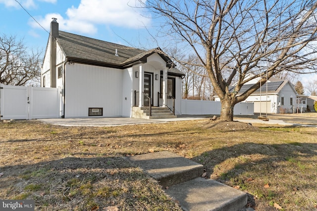 view of front of property featuring a front yard, a gate, fence, and a chimney