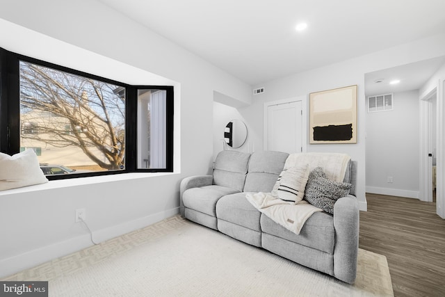 living room featuring visible vents, baseboards, and wood finished floors