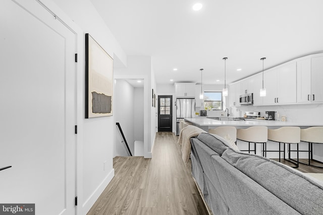 living room featuring recessed lighting, light wood-style flooring, and baseboards