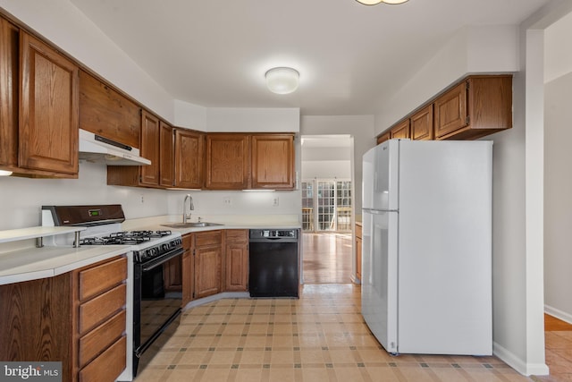 kitchen featuring range with gas stovetop, dishwasher, freestanding refrigerator, under cabinet range hood, and a sink