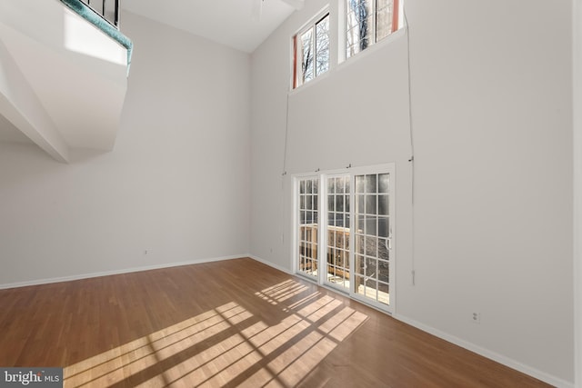 spare room featuring a high ceiling, wood finished floors, and baseboards