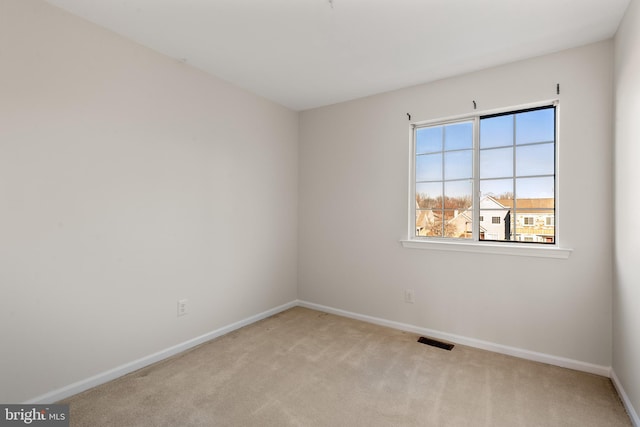 carpeted spare room with visible vents and baseboards