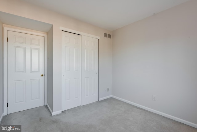 unfurnished bedroom with carpet floors, a closet, visible vents, and baseboards