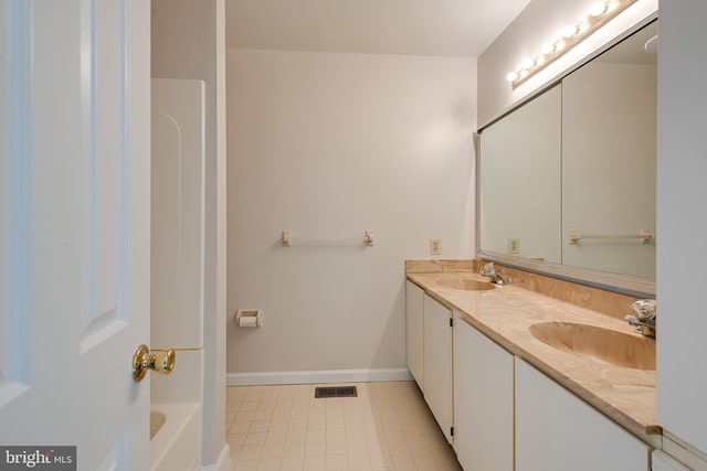 full bath featuring double vanity, a sink, a bathing tub, and baseboards