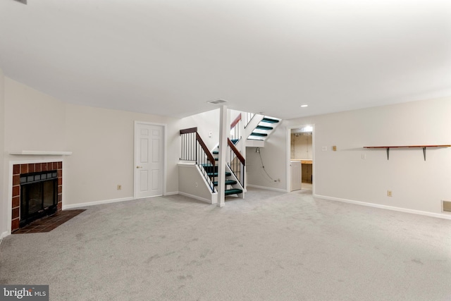 unfurnished living room with a tiled fireplace, stairway, carpet, and visible vents