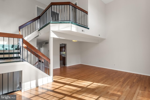 interior space featuring a high ceiling, stairway, wood finished floors, and baseboards