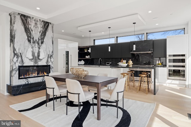 dining space with a fireplace, light wood-style flooring, and recessed lighting