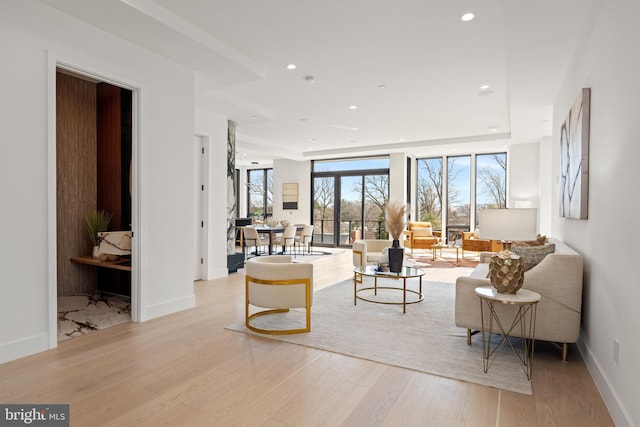 living area with baseboards, floor to ceiling windows, light wood finished floors, and recessed lighting