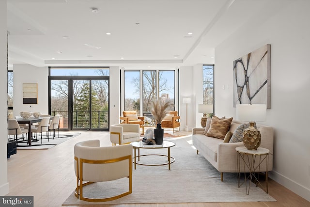 living area featuring a wall of windows, recessed lighting, baseboards, and wood finished floors