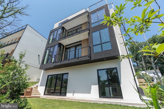 rear view of house featuring stairs and stucco siding