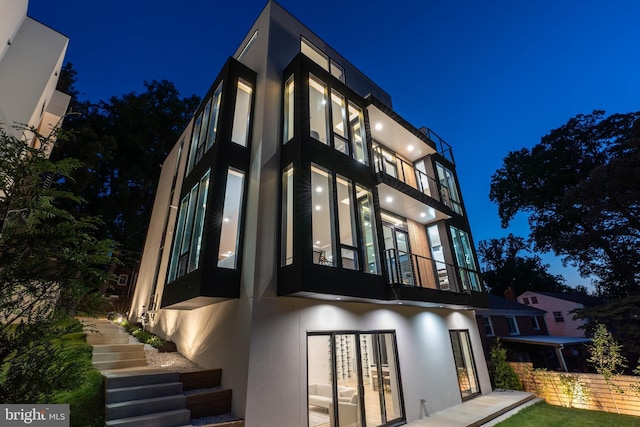 view of front of home with french doors, a balcony, and stucco siding