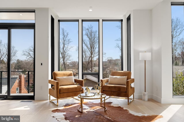 living area featuring expansive windows, plenty of natural light, and wood finished floors