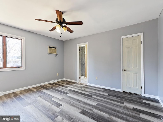 spare room with visible vents, baseboards, wood finished floors, and a wall mounted air conditioner